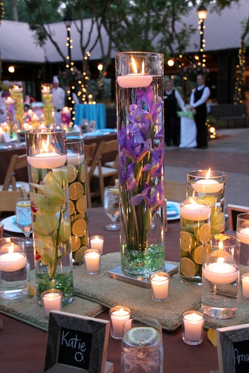 Glass cylinders filled with flowers water and floating candles 