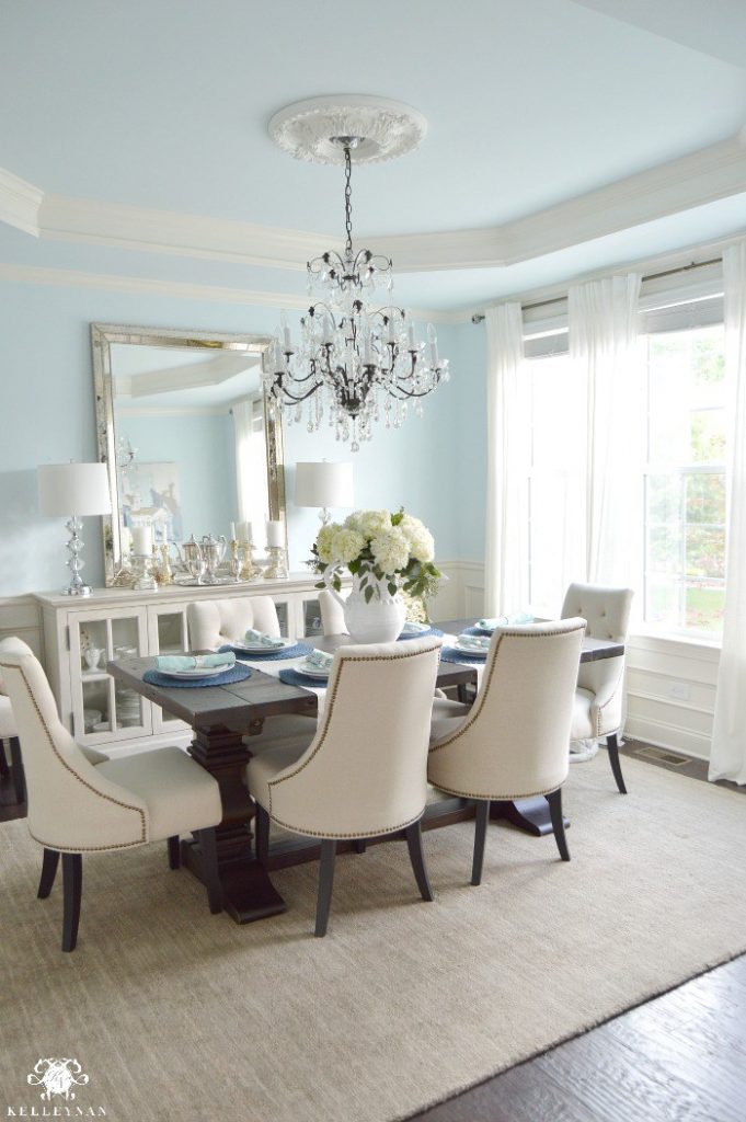 Blue-Elegant-Dining-Room-with-White-Hydrangeas-and-Vertical-Mirror-Over-Cream-Buffet