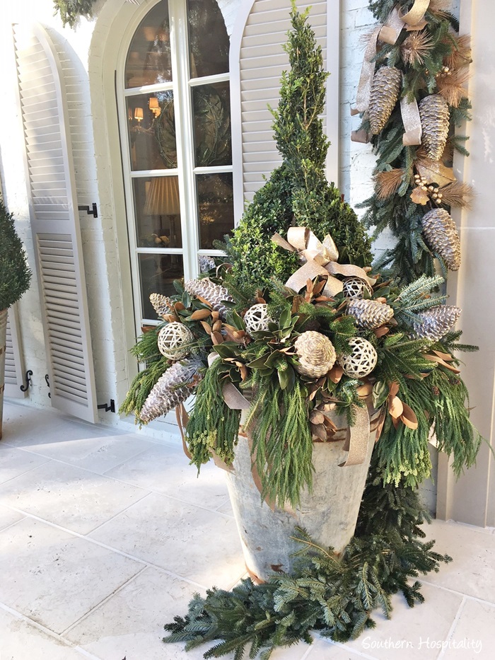 Zinc planter with boxwood and fresh evergreens decorated for Christmas on French Country home porch